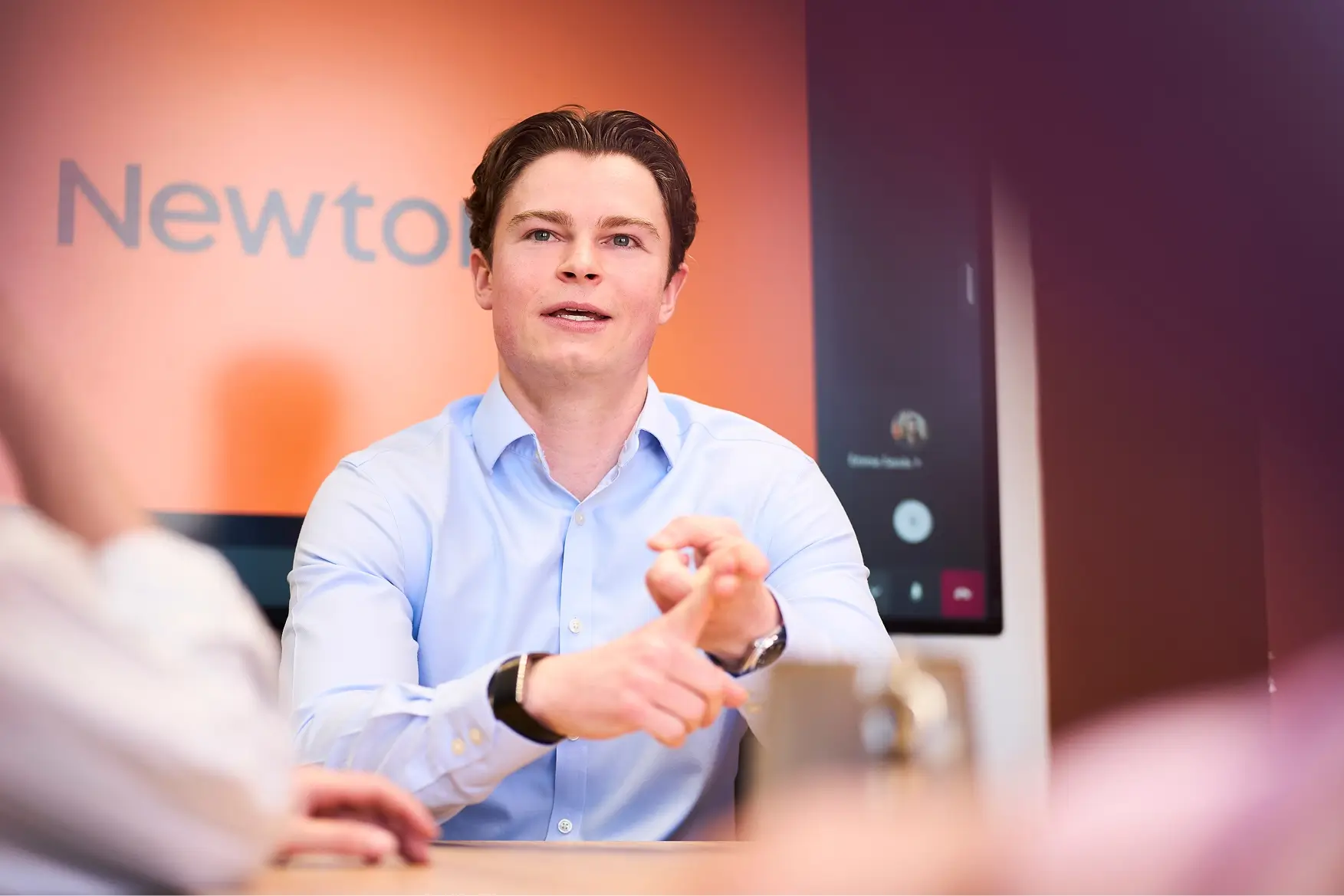 A man in a light blue shirt speaking during a meeting.